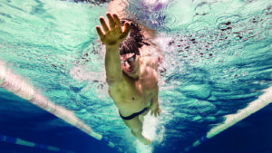 underwater picture of young swimmer in goggles exercising in swi
